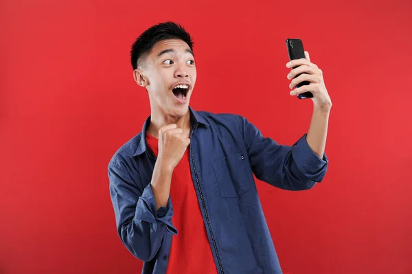 스마트폰을 휴대폰을 아시아 청소년 해피는 배경에 고립된 온라인에서 선물을 받는다 — 스톡 사진