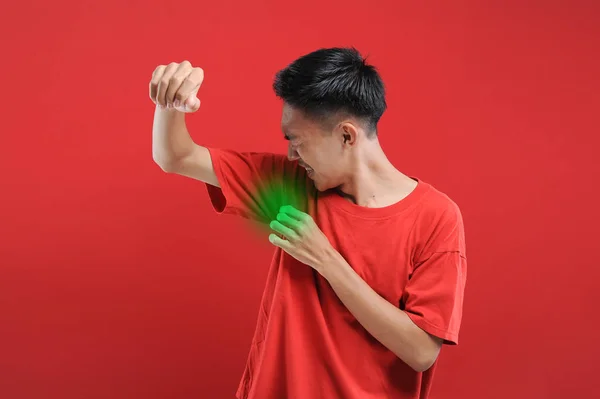 Hiperhidrozlu Asyalı bir adam koltukaltı altında terliyor, vücut konusunda kötü hissediyor, koku sorunu var, kırmızı arka planda izole edilmiş.