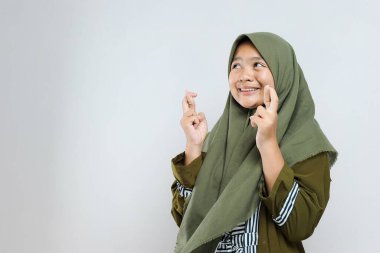 Müslüman tesettürlü genç ve güzel bir kadın, çok mutlu ve heyecanlı, kazanan bir jest yapıyor, gülümsüyor ve başarı için bağırıyor. Kutlama