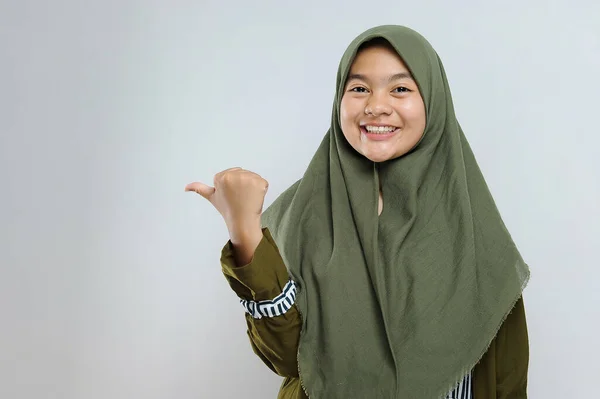 可爱的年轻美丽的穆斯林妇女指向复制空间 快乐的穆斯林妇女指着灰色背景上的复制空间 — 图库照片