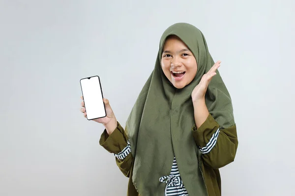 高兴的是 年轻的穆斯林妇女拿着空白屏幕的电话 与灰色隔离 — 图库照片