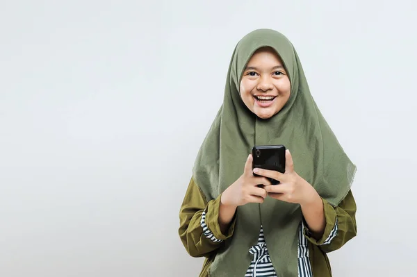 漂亮的穆斯林女人看着拿着灰色背景手机的相机 — 图库照片