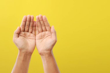 Ramazan 'daki tanrısına dua eden bir adamın elleri sarı arka planda izole edilmiş.