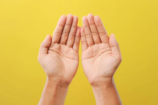 Ramazan 'daki tanrısına dua eden bir adamın elleri sarı arka planda izole edilmiş.