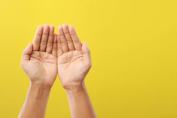 Ramazan 'daki tanrısına dua eden bir adamın elleri sarı arka planda izole edilmiş.