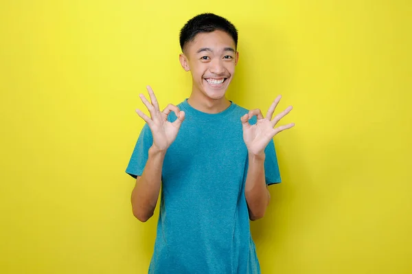 Portret Młodego Azjaty Optymizmem Pokazujący Gest Obiema Rękami Odizolowany Żółtym — Zdjęcie stockowe