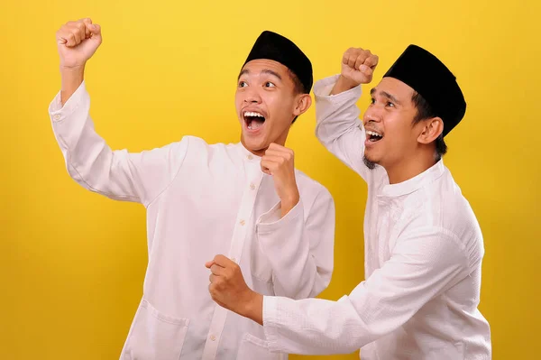 二つのハンサムな幸せなアジアのイスラム教徒のもう一つの目的は 黄色の背景に隔離された勝利のジェスチャーを示しながら 顔を驚かせた — ストック写真