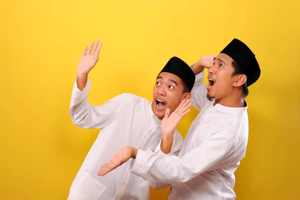 两个英俊的快乐的亚洲穆斯林的另一个姿势 满脸惊讶 同时表现出得意洋洋的姿态 因黄色背景而被隔离 — 图库照片
