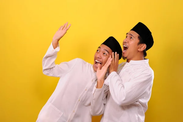 二つのハンサムな幸せなアジアのイスラム教徒のもう一つの目的は 黄色の背景に隔離された勝利のジェスチャーを示しながら 顔を驚かせた — ストック写真