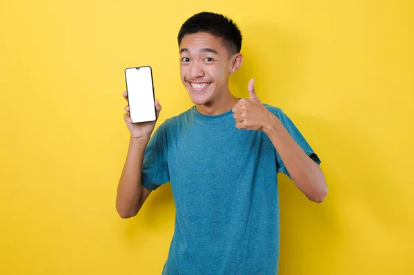 快乐的年轻亚洲少年 在摄像机前展示白色手机屏幕 有好的标志 黄色背景隔离 — 图库照片