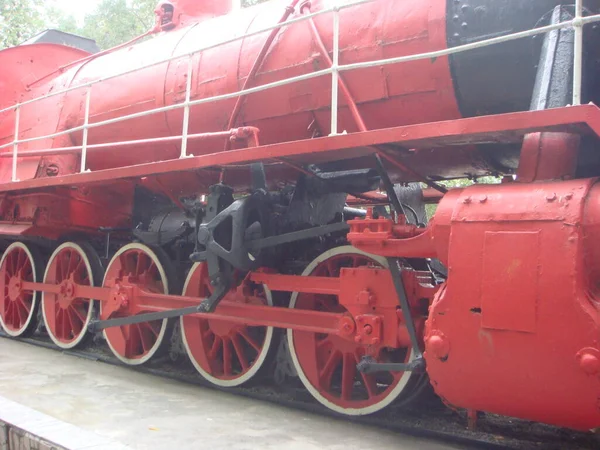 Old Russian locomotive. Steam locomotive with red wheels. Retro locomotive on rails. Old rare Soviet train transport. Red wheels of an old locomotive on the rails close-up.