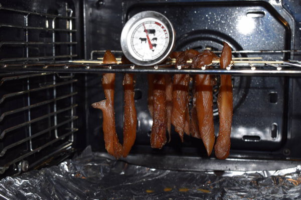 Soft focus. Smoked ham in the oven. Production in the oven smokehouse. Drying in the oven delicacies for dogs. Raw meat on the oven rack. Cooking treats for dogs at home.