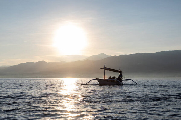 Balinese boats with tourists during sunset colors over the calm 