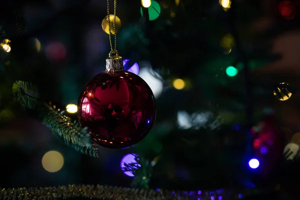Red christmas ball hanging on a christmas tree with blurred lights on background — 스톡 사진