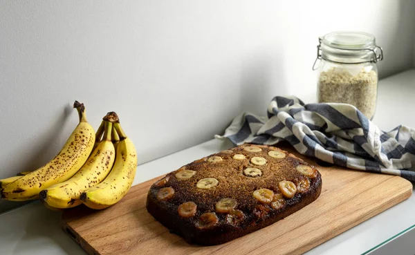 Homemade banana bread over a wooden table with bananas as decoration