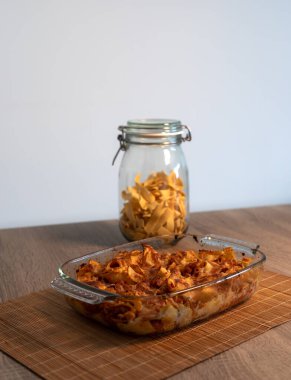 Bambu hasırının üzerinde vejetaryen bolonez bulunan rendelenmiş tagliatelle kristal tepsisinin ve kopya alanı ve beyaz arkaplanı olan ahşap bir masanın ön görüntüsünü kapat.