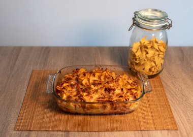 Bambu hasırının üzerinde rendelenmiş tagliatelle ve vegan bolonez ile kristal bir tepsinin ön görüntüsü ve kopya alanı ve beyaz arkaplanı olan ahşap bir masa.