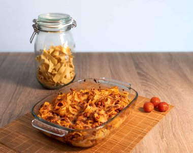 Bambu hasırının üzerinde vejetaryen bolonez bulunan rendelenmiş tagliatelle kristal tepsisinin ve kopya alanı ve beyaz arkaplanı olan ahşap bir masanın ön görüntüsünü kapat.