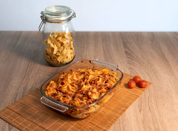 Bambu hasırının üzerinde vejetaryen bolonez bulunan rendelenmiş tagliatelle kristal tepsisinin ve kopya alanı ve beyaz arkaplanı olan ahşap bir masanın ön görüntüsünü kapat.