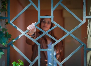 Metal parmaklıkların arkasındaki güzel genç kadın bulanık