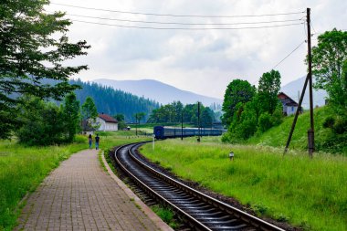 Bir adam ve bir kız, bir dağ köyünde giden trenden sonra platformda el ele gidiyorlar. Dağ köyü ve tren. Dağlarda küçük bir köydeki tren istasyonu.
