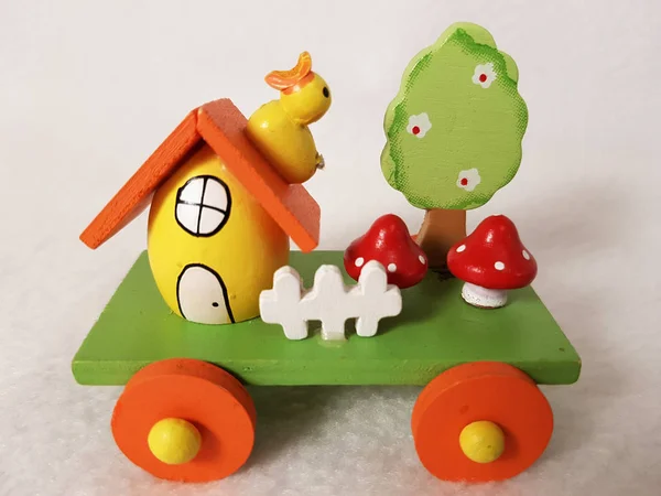 Easter train and egg-house, duckling, mushrooms, a tree in flowers and a white fence - wooden holiday transport toy, yellow, green, red and orange colors, platform trailer on wheels. Photo with copy