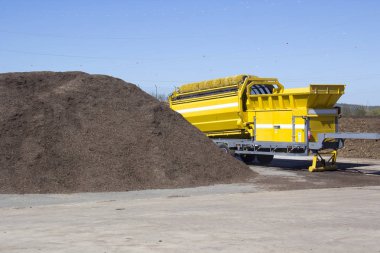 Malç yeşil geri dönüşüm tesisinde kompost yapmak için endüstriyel bir değirmeni girecek şekilde hazır yığını