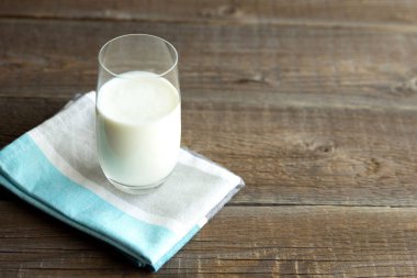 Organik kefir, ayran ya da süt, cam bardağa dökülen tahta bir masanın üzerindeki pamuk peçetenin üzerinde duruyor. Pribiyotik Kaynağı. Metin için yer