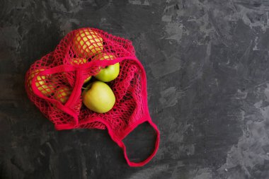 Siyah arka planda, kırmızı, yeniden kullanılabilir pamuk iplik torbasında taze sarı elmalar. Çevreye önem vermek. Sıfır kayıp. Boşluğu kopyala