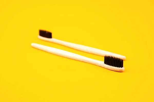 Two toothbrushes made of natural materials lie on a yellow background. Place for text. Refusal of plastic. Zero waste. Oral care — Stock Photo, Image