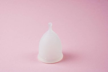 Pembe arka planda beyaz silikon kadın adet bardağı. Ziyan yok. Yeniden kullanılabilir ürünler. Metin için yer