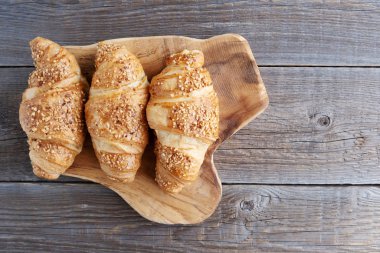 Tahta bir masanın üzerinde üç tane taze Fransız kruvasanı var. Fırın. Sobanın çörekleri. Kahvaltıda. Boşluğu kopyala.