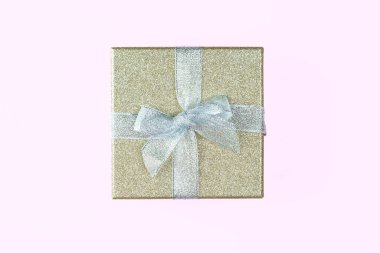 Gümüş yay ile altın pullara sarılmış bir hediye. Yukarıdan bak. Tasarım ögesi ya da tebrik kartı. Pembe arka plan. Metin için yer.