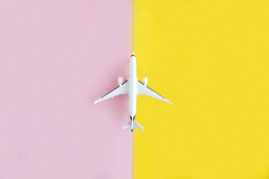 Sarı ve pembe arka planda beyaz bir uçak modeli. Seyahat, uçuş konsepti. Mesaj için yer. Tasarım için tasarım. Minimalizm.