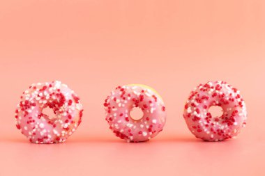 Pembe arka planda pembe kremalı üç taze çörek. Sağlıksız lezzetli yemek kavramı. Fırın ürünleri. Metin için yer.