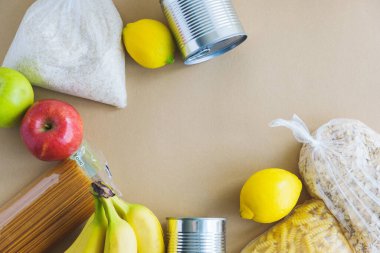 Yiyecek yardımı, bağış. Pirinç, makarna, yulaf ezmesi, elma, konserve yiyecek, limon kahverengi bir zemin üzerinde yatar.