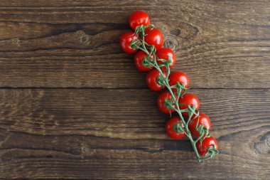 Bir dalda kiraz domatesleri, ahşap bir kırsal kahverengi arka planda yatıyor. Mesaj için yer. yatay yönelim
