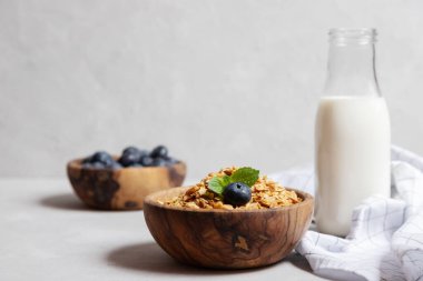 Ev yapımı tahıl gevreği ya da yulaf ezmesi taneli ahşap bir kase yanında yabanmersini ve bir şişe taze süt. Kırsal kahvaltı. Uygun beslenme.