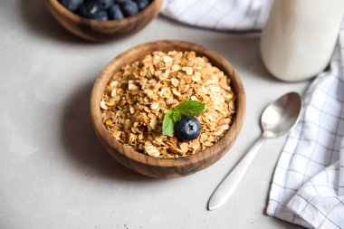 Tahta bir kasede taze tahıllı tahıl gevreği ya da yaban mersinli yulaf ezmesi ve yakınlarda bir bardak süt. Çocuklar için sağlıklı bir kahvaltı..