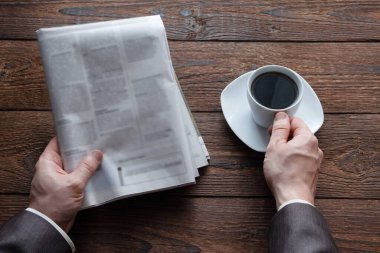 Bir Alman gazetesi ve bir fincan sade kahve tutan erkeklerin üst görüntüsü. Sabahları haberleri okuyorsun. Finans, iş. Metin için yer.