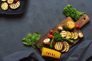 Ahşap kesme tahtasında ızgara sebze. Vejetaryen ızgara menüsü konsepti. Mesaj için yer. Koyu arkaplan