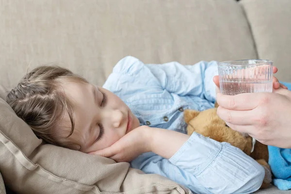 Mignon triste malade blond chevelu fille caucasienne prend un verre d'eau. Prendre des pilules, des antibiotiques. Traitement à domicile — Photo