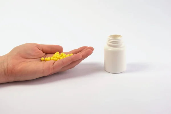 Hand with pills, pills, vitamins and an adjacent white jar. The purpose of treatment, medications, vitamins. Taking painkillers. Copy space — Stock Photo, Image