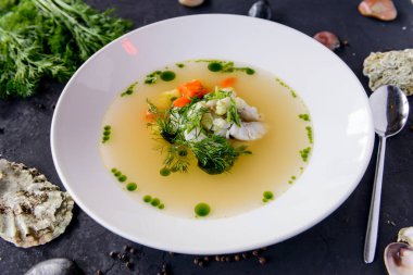 Deniz mahsulleri çorbası bir beton zemin üzerine beyaz bir tabak içinde