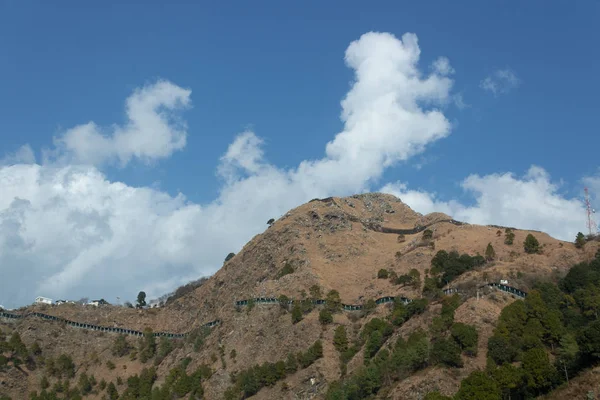 Baixo ângulo ampliado em tiro largo de uma montanha com galpão estradas cobertas e céu azul nublado no fundo . — Fotografia de Stock