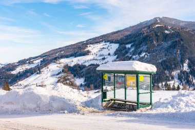 Avusturya otobüs durağı, kayak bölgesi Schladming-Dachstein, karla kaplı yol, ağaçlar ve dağlar..
