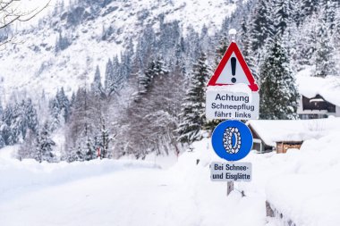 Trafik levhası, Bei Schnee ve Eisgltte. Mavi uyarı bilgisi: kar zinciri zorunluluğu. Kış zamanı, karla kaplı yollar, ağaçlar. Styria, Avusturya