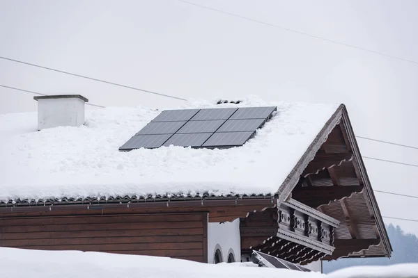 Güneş panelleri, fotovoltaik modüller, çatısı karla kaplı bir evin pv panelleri. Dağlarda güneşten elektrik geliyor..