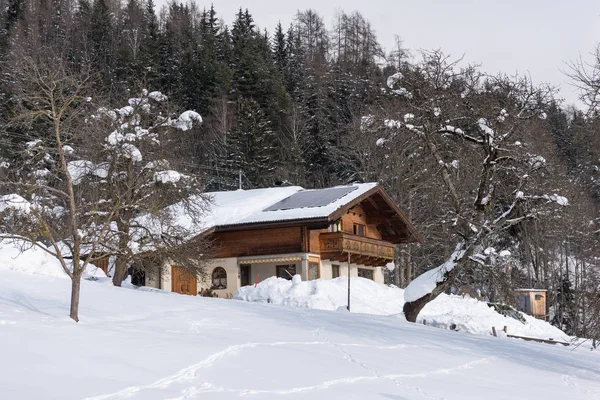 Panneaux solaires photovoltaïques PV sur un toit de maison enneigé. L'électricité du soleil pendant l'hiver. Maison dans les montagnes avec des arbres enneigés à l'arrière-plan . — Photo