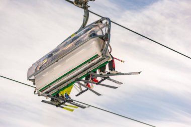 Mavi gökyüzüne karşı bir sandalyede dört kayakçı, aşağıdan, kayak yamacından görüldü. Kayak merkezi Schladming Dachstein, Styria, Avusturya